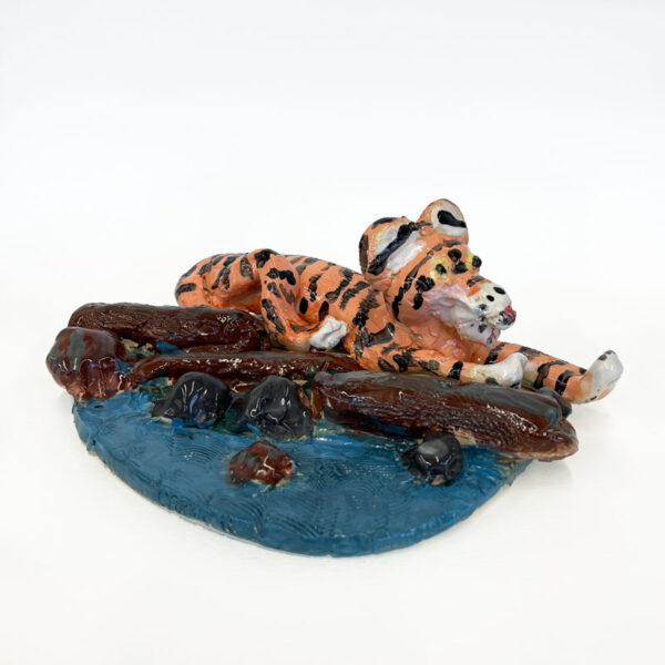 Ceramic sculpture of a tiger laying by a river by Carrie Reed