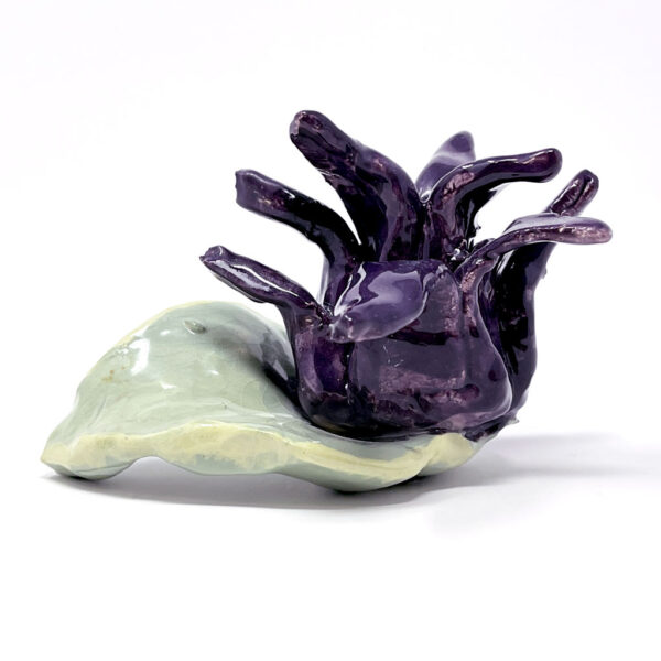 Ceramic sculpture of a spikey purple flower with a single green leaf