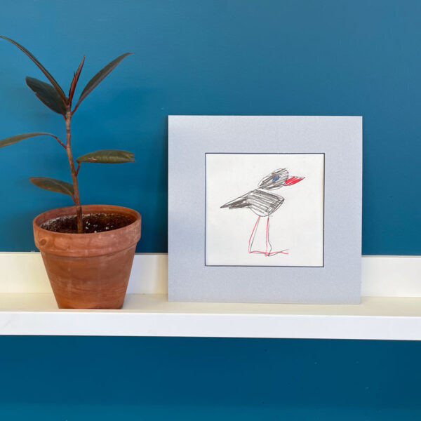 Bird drawing in a light blue-grey mat on a white shelf