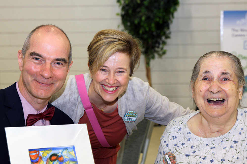 Artist Uli smiling with two guests at the luncheon