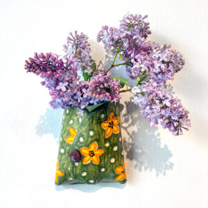 Green ceramic wall vase with tiger lily pattern, full of lilacs