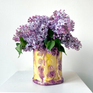 Yellow and purple vase with lilacs in it