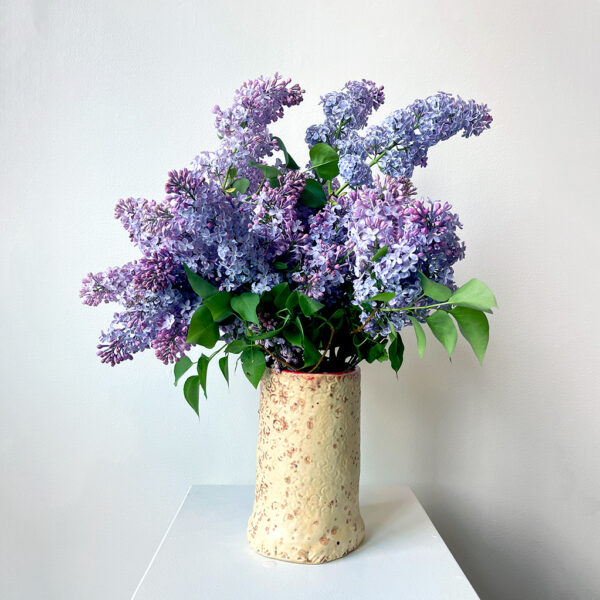 Cream coloured vase full of lilacs