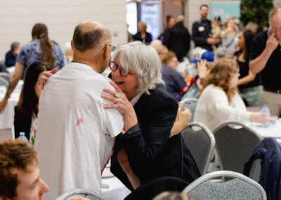 Two people hugging in a room full of guests
